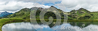 Panorama of water reservoir for providing snowmaking to ski slopes in winter in alpen ski resort Obertauern in summer Stock Photo