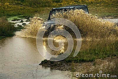 Water splash in off-road racing. SUV race on dirt. Wheel close up in a countryside landscape with a muddy road. Stock Photo