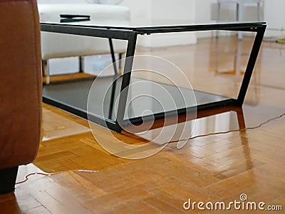 Water spreading / flooding on living room parquet floor in a house - damage caused by water leakage Stock Photo