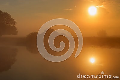 Water surface of river in sunny summer morning with fog and reflection of orange sun. River landscape at sunrise Stock Photo