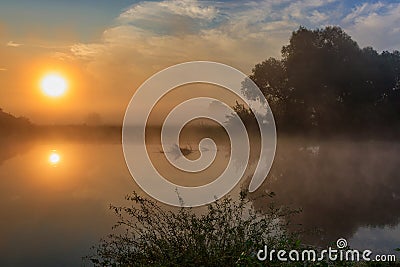 Water surface of river at sunrise with reflection of orange sun. River landscape in sunny summer morning Stock Photo