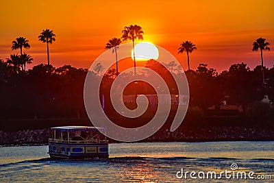 Water taxi sailing on illuminated lake on colorful sunset at Lake Buena Vista area. Editorial Stock Photo