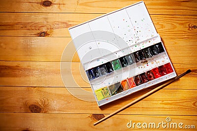 Watercolor aquarell paints in box with brush on wooden background Stock Photo