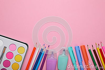 Watercolor palette, colorful markers and pencils on pink background, flat lay. Space for text Stock Photo