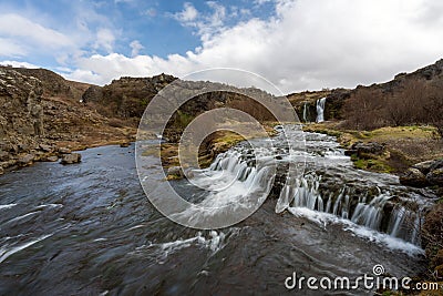 Waterfall cascade in the area of Gjain in Porsdalur in the Icelandic highlands. Oblue cloudy sky. Long exposure shot of the river. Stock Photo