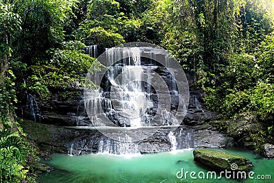 Waterfall cascade in Tropical Rainforest With Big Rock Cover with Green Moss After Rain. Taken in Cariu Jungle Bogor at Wet Season Stock Photo
