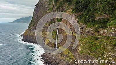 Waterfall falling into ocean from volcanic cliffs. Stock Photo