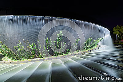 Waterfall flows in streams into granite bed of artificial river. Fountain in form of huge bowl Editorial Stock Photo