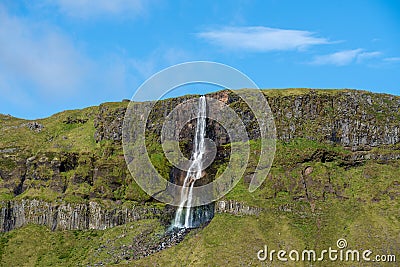 Waterfall flushing down a green mountainside Stock Photo