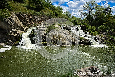 The waterfall on the river flows through and over the rocks cove Stock Photo