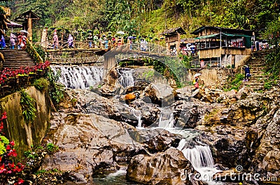 Waterfall from rocks with a wooden bridge across in the mountains of Sapa. Sapa, Vietnam - 01/02/2020 Editorial Stock Photo