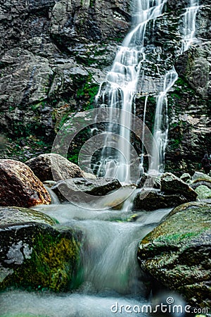 Waterfall white water stream falling from mountains at day from low angle Stock Photo