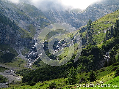 Waterfall runlets into alpine mountain valley summer season landscape Stock Photo