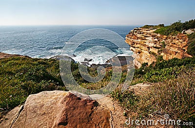 Waterfront lookout on hill with idyllic and amazing seaside landscape of bluff with shrubs, jagged coast with rocks, ocean horizon Stock Photo