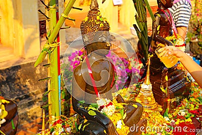 Watering Buddha statues with scented water and flower petals during Lao New Year - Pii Mai Lao - Song Kran - Water Festival in Apr Stock Photo