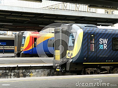 Waterloo station in London with three electric trains in contrasting colourful liveries Editorial Stock Photo