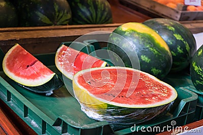 Watermelon ready to sell cut in half and pieces in a green plastic box at local market. Tropical healthy product open to being Stock Photo