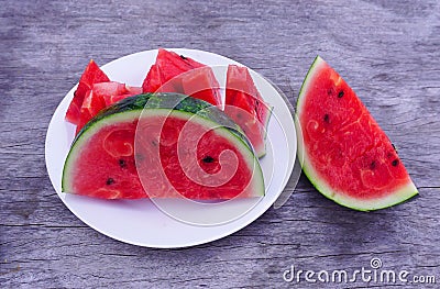 Watermelon slices on a white plate laid on a wooden background, fruit, high in vitamins, good for health Stock Photo