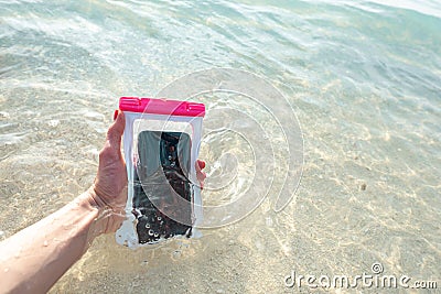 Waterproof case on a smartphone, phone for taking pictures under water. Phone in the waterproof case underwater, on the sands Stock Photo