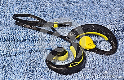 Waterproof earphones, yellow and black, beaded with water. Stock Photo