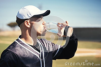 Waters awesome but you cant quench his thirst for baseball. a young man drinking water after playing a game of baseball. Stock Photo