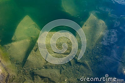 The waters of the basalt lake the stones in the lake are covered with algae clear and pure water Stock Photo