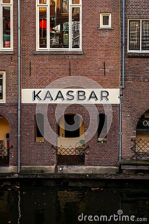 Waters edge view of restaurant bar sign Kaasbar, at an old ancient red brick building by the canal in Utrecht. Editorial Stock Photo