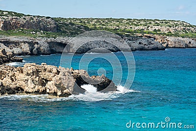 Wave hits sea cliff in blue lagoon Stock Photo