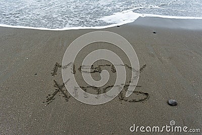 Merry Xmas hand written in the sand with the sea in the background Stock Photo