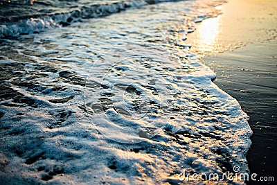 Wave of the ocean sea on the sand beach at the sunset light. Stock Photo