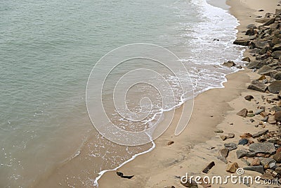 Wave on the sand beach with stones Stock Photo