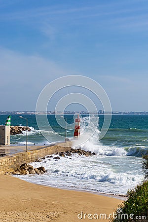 Wave splashes against lighthouse in Lagos, Portugal Stock Photo