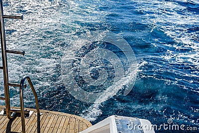 Wave trace with white foam on a water surface behind of fast moving yacht Stock Photo
