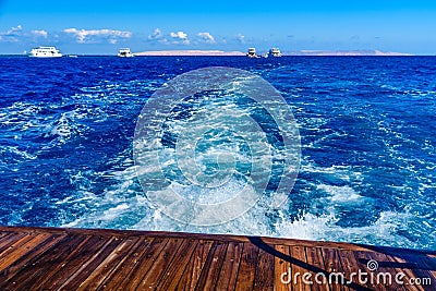 Wave trace with white foam on a water surface behind of fast moving yacht Stock Photo