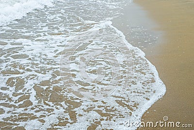 Waves breaking on shore of the sea. closeup of sea foam on wet sand Stock Photo
