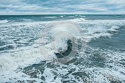 Waves Breaking and Spraying at High Seas and Strong Winds. Storm at the sea in autumn cloudy rainy day Stock Photo