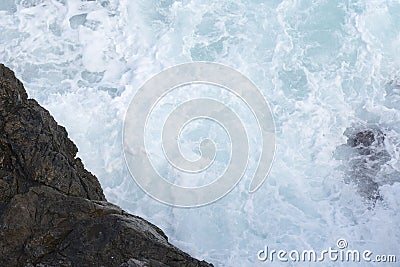 The waves breaking on a stony beach, forming a spray. Wave and splashes on beach. Waves crashing onto rocks. Stock Photo