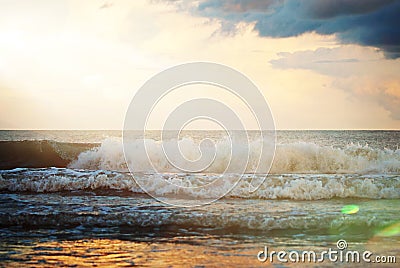 Waves crashing on shore with a gorgeous sunflare hitting the water. Stock Photo