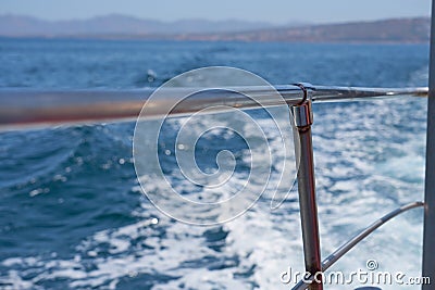 Waves with foam overboard the ship with the coast in the background. Stock Photo