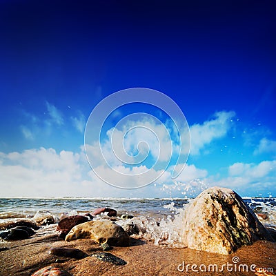 Waves hiting rocks on the sunny beach Stock Photo