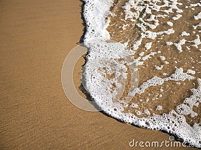 Waves lapping against sand on the California coast. Sea foam and sandy beaches in summer sunlight for travel blogs, website banner Stock Photo