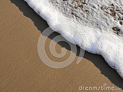 Waves lapping against sand on the California coast. Sea foam and sandy beaches in summer sunlight for travel blogs, website banner Stock Photo