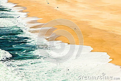 Waves of the sea reaching the golden sand Stock Photo