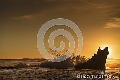 Waves smashing against the rocks during sunset Stock Photo