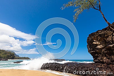 Waves splashing over lava rock on beautiful sandy tropical beach Stock Photo