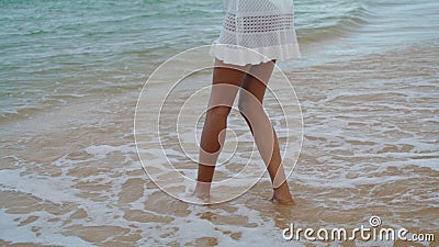 Waves washing woman legs at calm shore. Slim girl playing touching ocean sand in Stock Photo