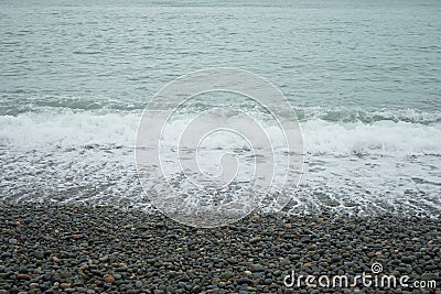 Waves of water with bubbles on a pebble seashore Stock Photo