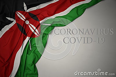 waving national flag of kenya on a gray background with text coronavirus covid-19 . concept Stock Photo