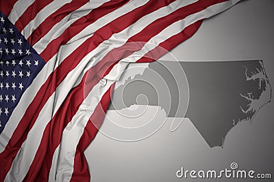 Waving national flag of united states of america on a gray north carolina state map background. Stock Photo