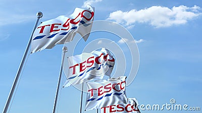 Waving flags with Tesco logo against sky, editorial 3D rendering Editorial Stock Photo